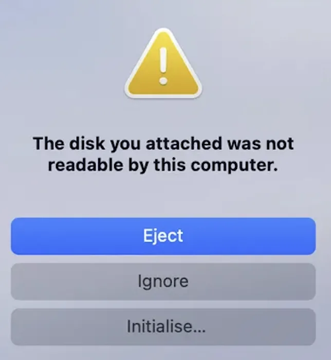 The macOS alert shown without Luksmith: &ldquo;The disk you attached was not readable by this computer,&rdquo; offering only Eject, Ignore and Initialise.